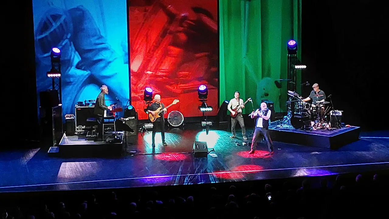 Ian Anderson al flauto con i Jethro Tull su un palco illuminato di blu, rosso e verde