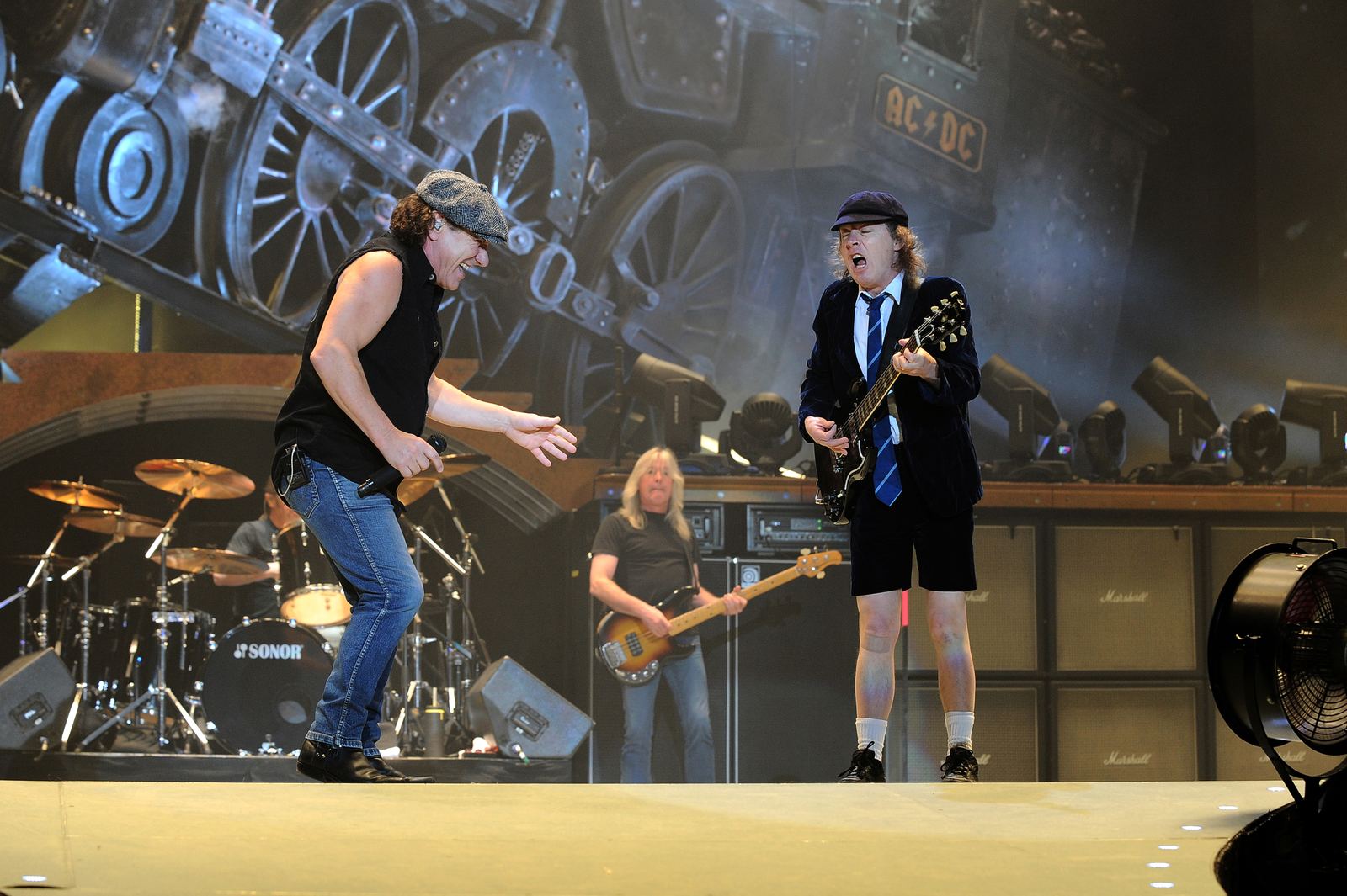 Brian Johnson e Angus Young degli AC/DC sul palco durante un concerto, con Cliff Williams al basso sullo sfondo
